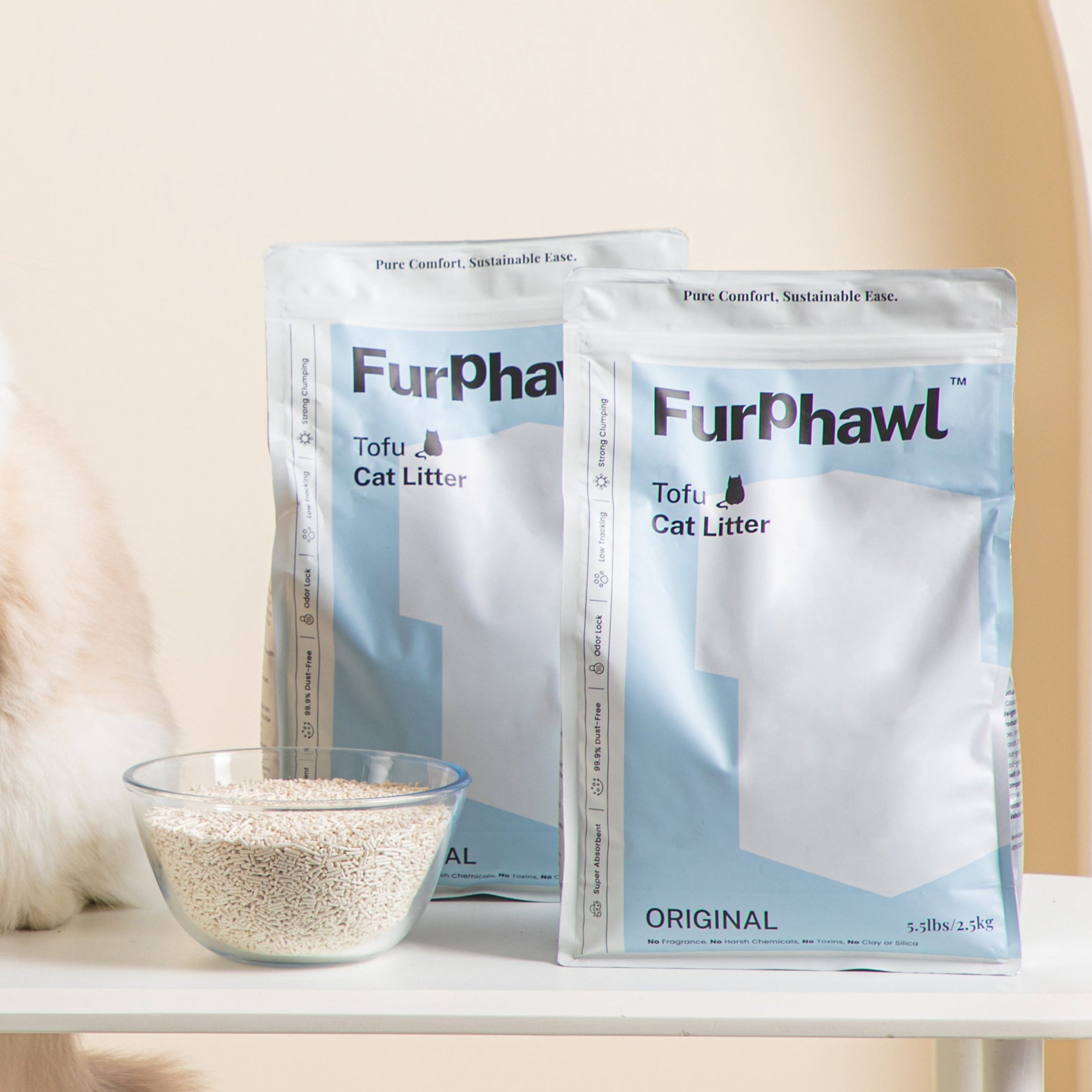 Cat sitting on a table with Furphawl Tofu cat litter packages and a bowl of litter in the background.